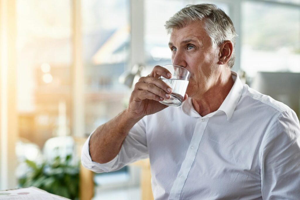 Neujahrsvorsätze für strahlend gesunde Zähne: Mann trinkt Wasser